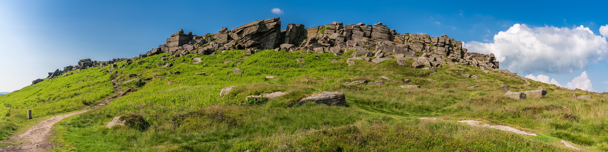 Walkers approaching Stanage Edge near Hathersage in the Peak District, Derbyshire, England, with rolling moors and rugged East Midlands countryside in view